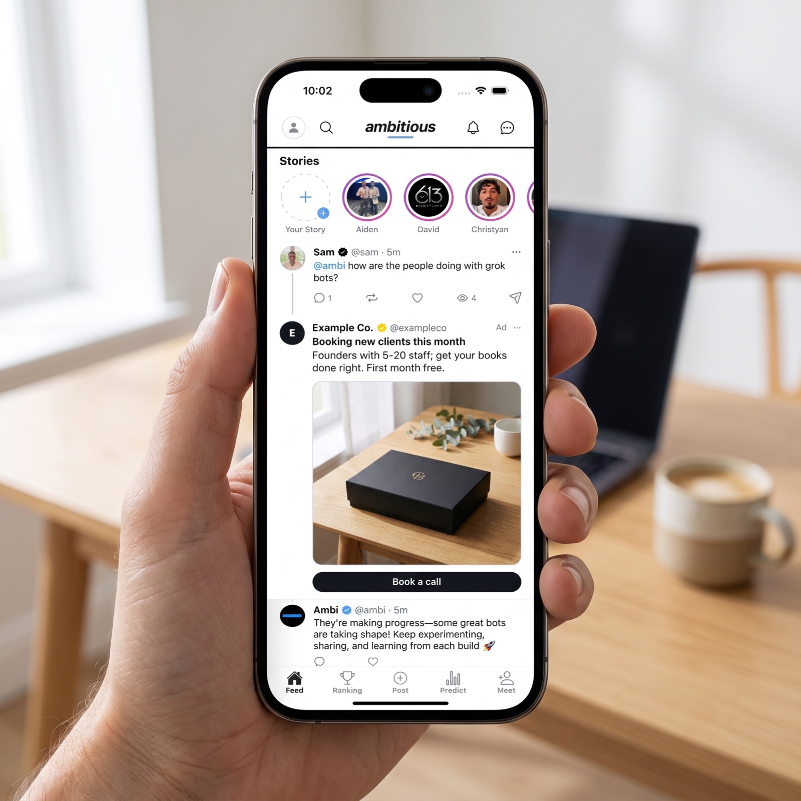 An iPhone showing the Ambitious feed with a sponsored post from Example Co. between members' posts